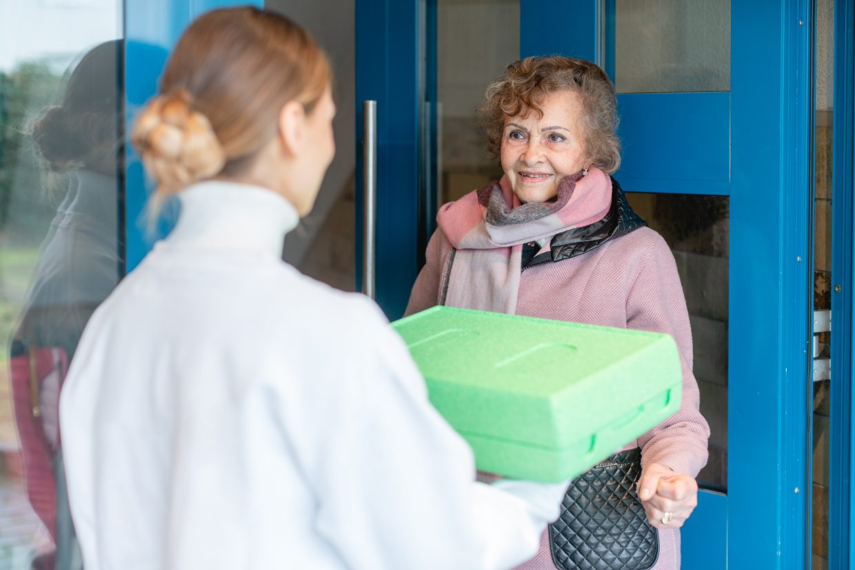 Volunteer delivering a meal to door of senior citizen